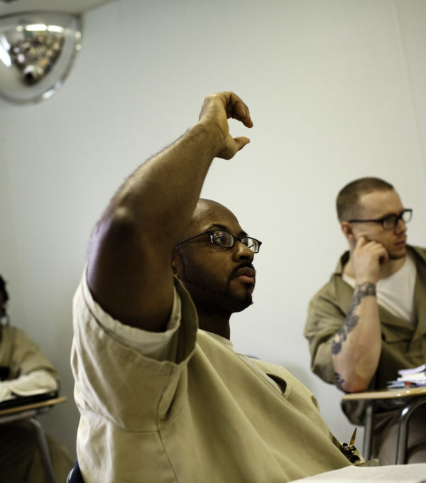 Man in classroom raising hand.