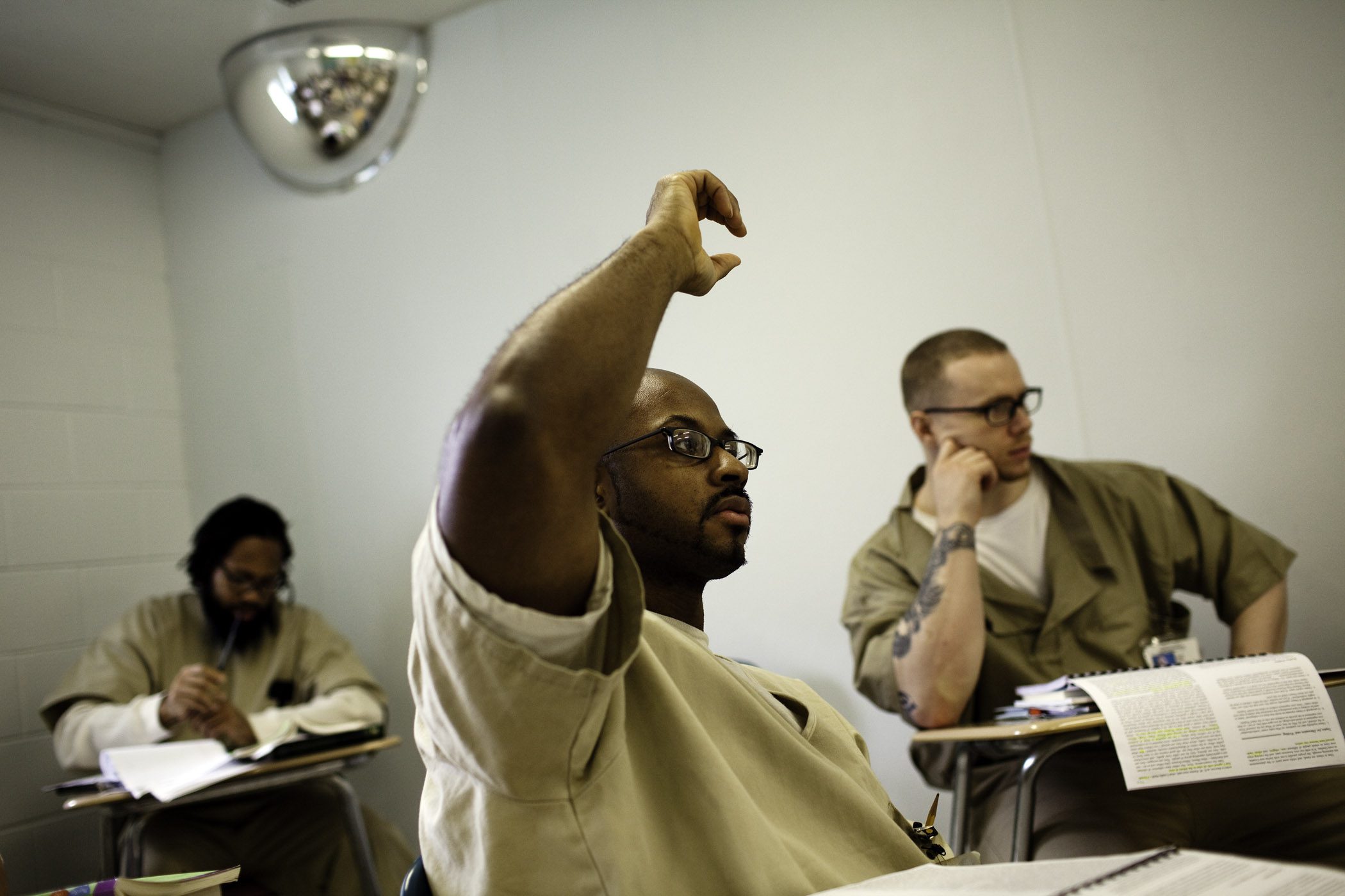 Man in classroom raising hand.