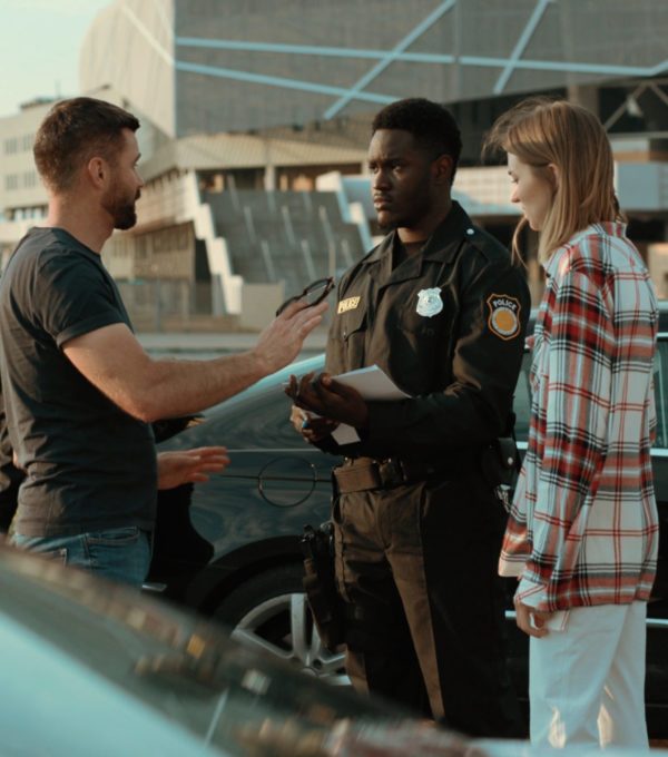 Photo of a woman and man being helped by a police officer