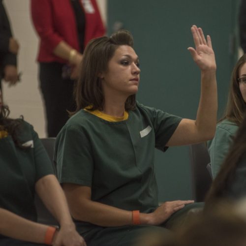 woman raises hand in Colorado corrections facility