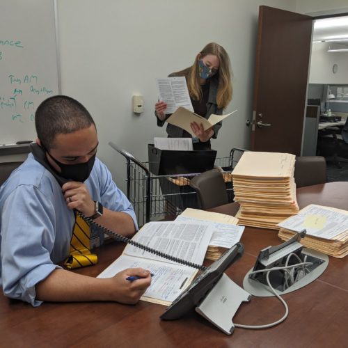 Assistant District Attorney Joshua Sotomayor and intern Amanda Murphy work in an office with masks on.