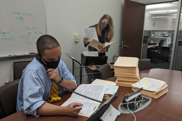 Assistant District Attorney Joshua Sotomayor and intern Amanda Murphy work in an office with masks on.