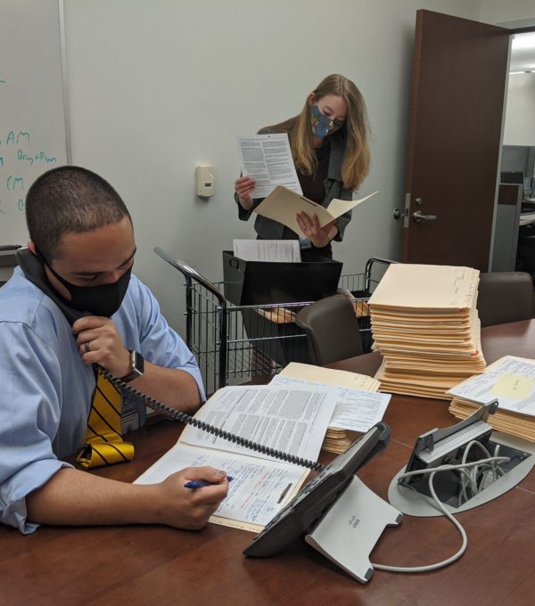 Assistant District Attorney Joshua Sotomayor and intern Amanda Murphy work in an office with masks on.
