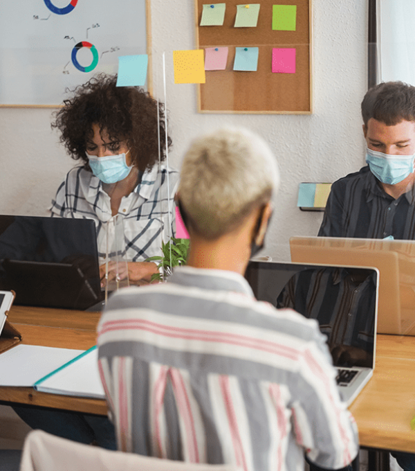 Four people sitting in office with masks for safety precaution