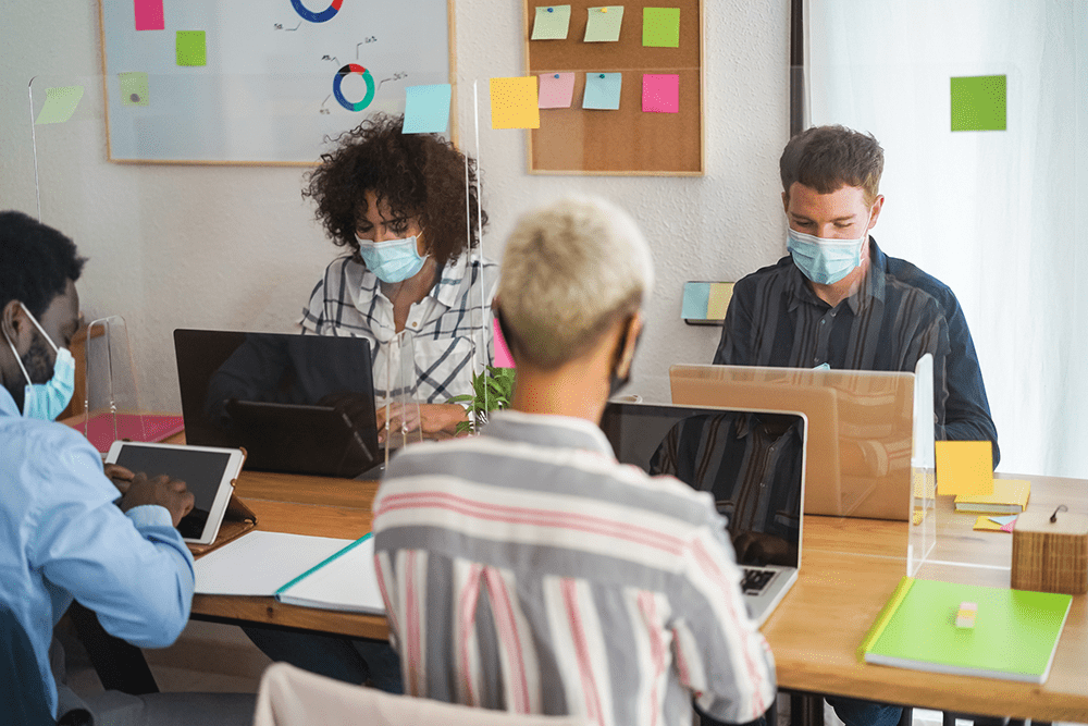 Four people sitting in office with masks for safety precaution
