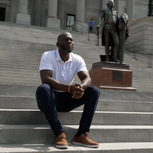Man sitting on steps of government building.