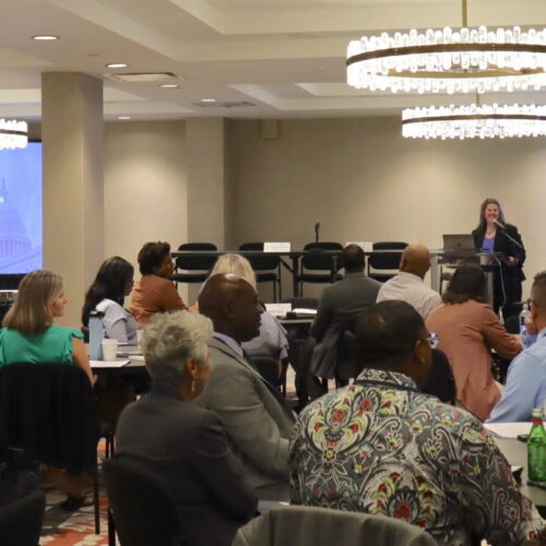 OJJDP Administrator Liz Ryan speaks at the podium to give opening remarks at the Second Chance Act Addressing the Needs of Incarcerated Parents and Their Minor Children grantee convening.