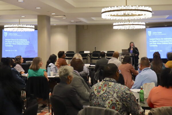 OJJDP Administrator Liz Ryan speaks at the podium to give opening remarks at the Second Chance Act Addressing the Needs of Incarcerated Parents and Their Minor Children grantee convening.