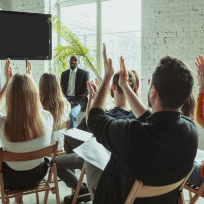 a group of people clapping their hands in front of a facilitator and screen