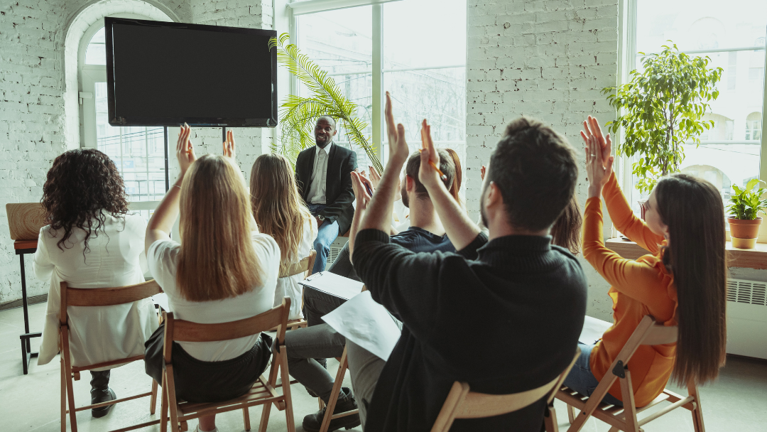 a group of people clapping their hands in front of a facilitator and screen