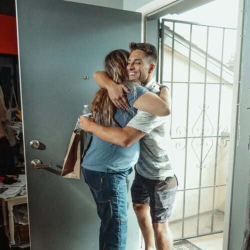 Man and woman hug in the entrance of an apartment