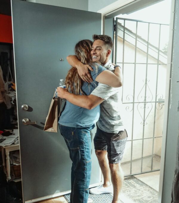 Man and woman hug in the entrance of an apartment