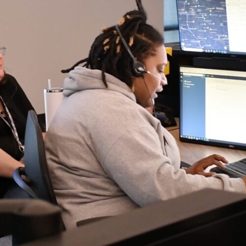 Woman wearing a headset and typing on a computer.