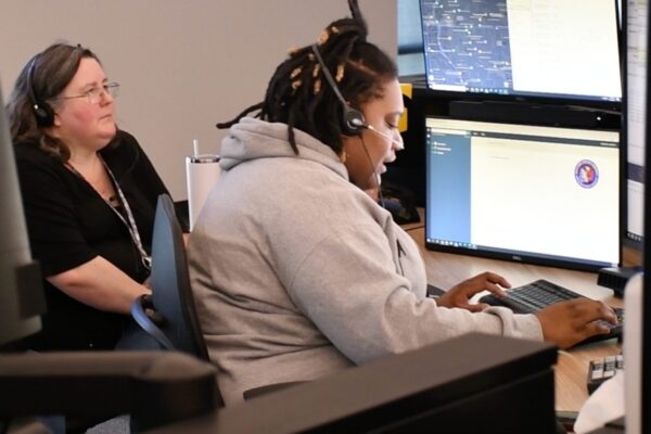 Woman wearing a headset and typing on a computer.
