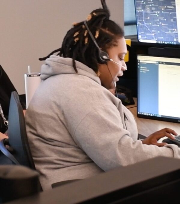 Woman wearing a headset and typing on a computer.