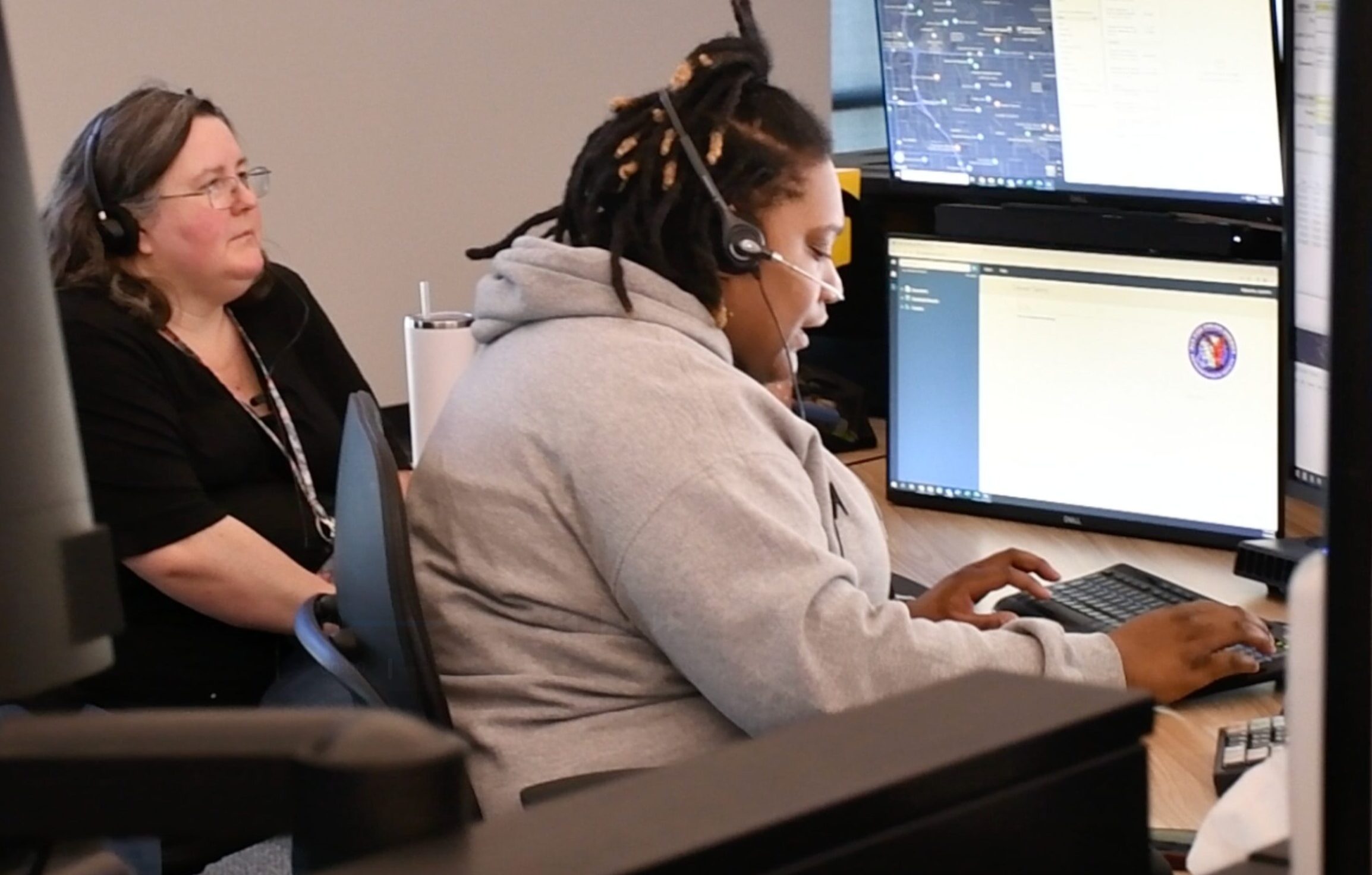 Woman wearing a headset and typing on a computer.