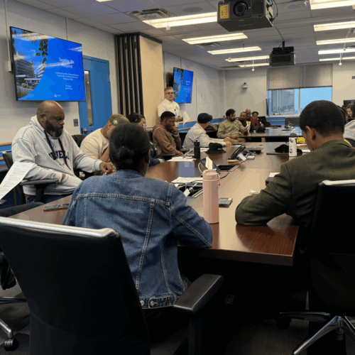 Several people are seated around tables and engaged in discussion.