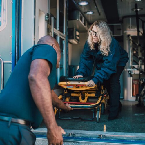 Man pulling out a stretcher from an ambulance.
