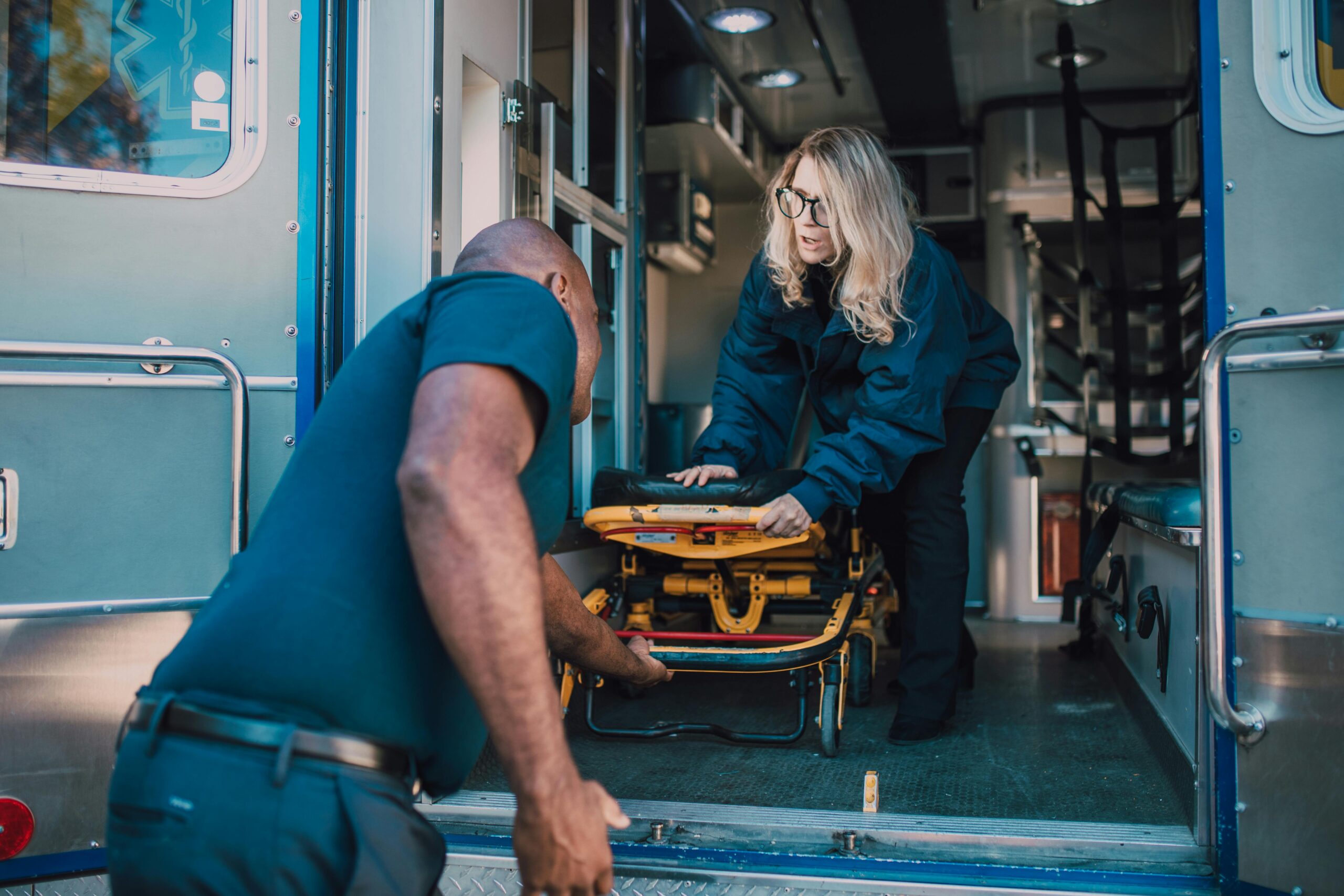 Man pulling out a stretcher from an ambulance.
