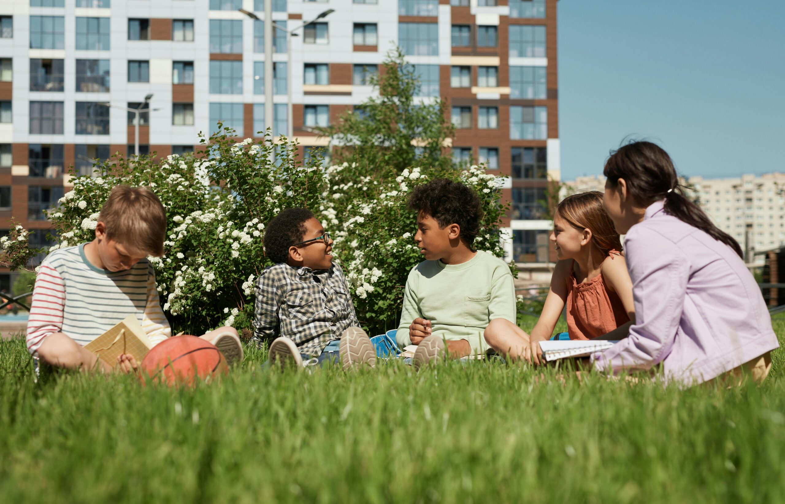 Kids sitting in the grass in a city