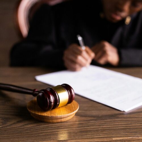 Female judge writing on a piece of paper on desk with gavel