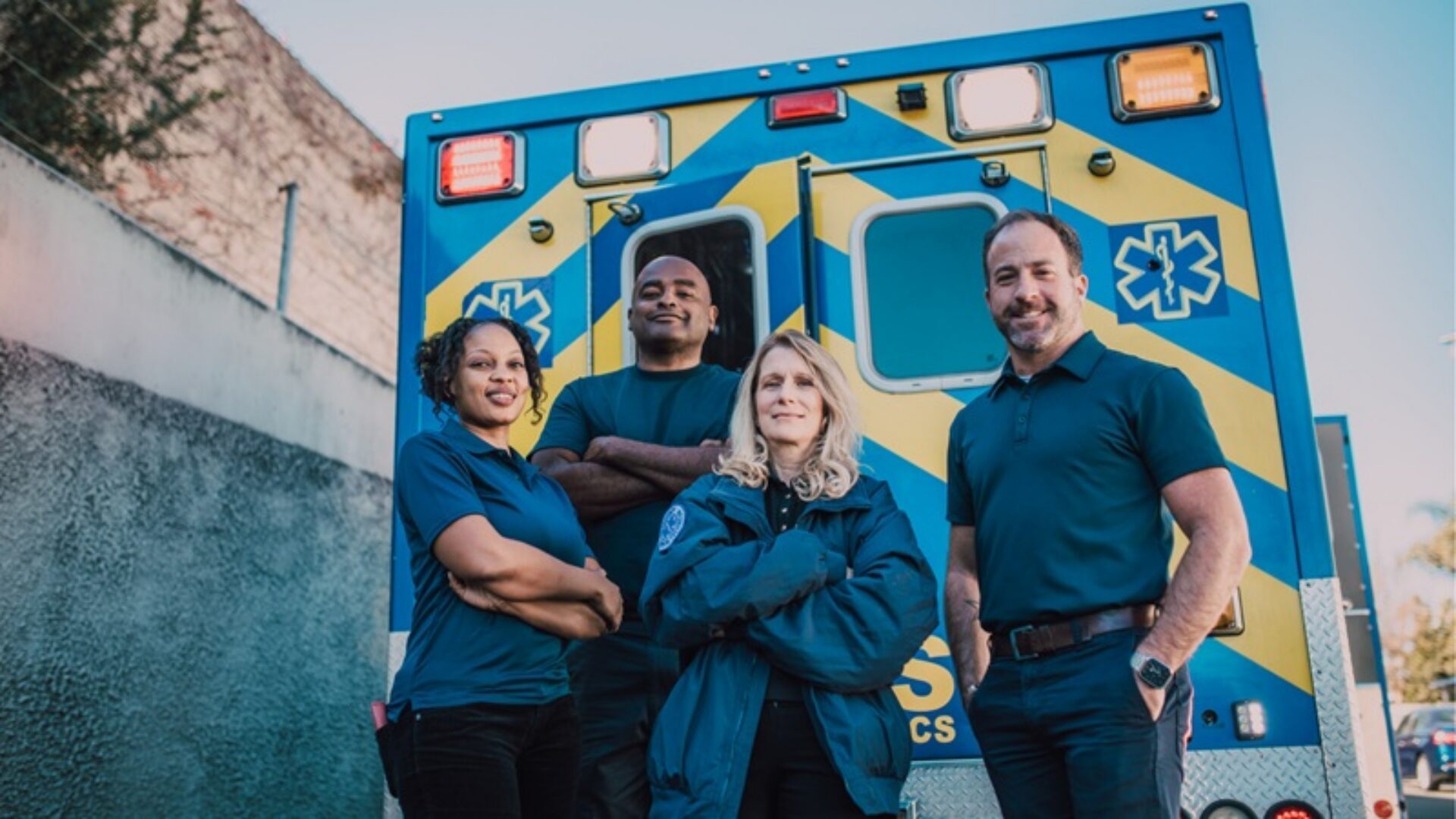 Four crisis responders standing in front of an ambulance.