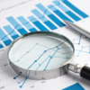 Magnifying glass on papers with graphs and charts
