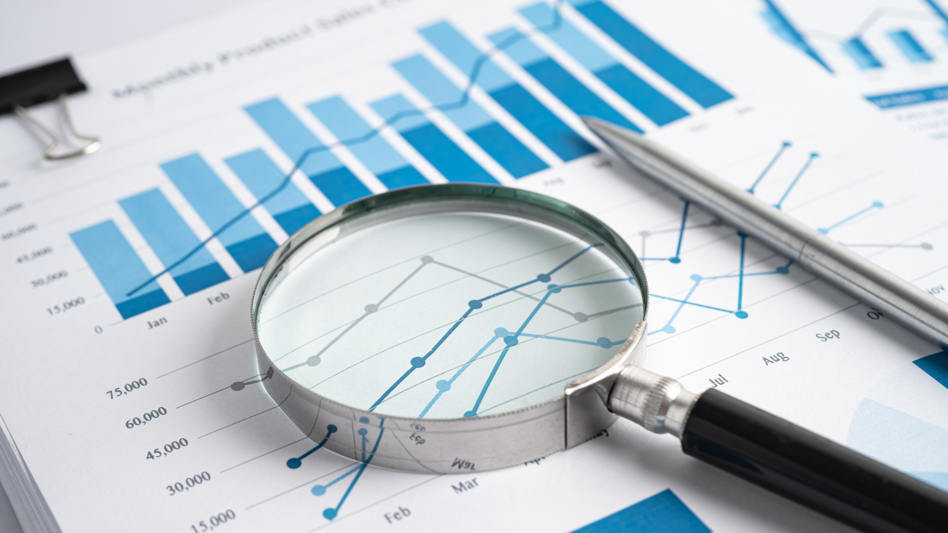 Magnifying glass on papers with graphs and charts